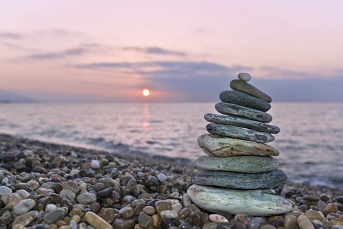 How Are Holistic Therapies Used in Addiction Treatment - stacked river rocks on beach at sunset