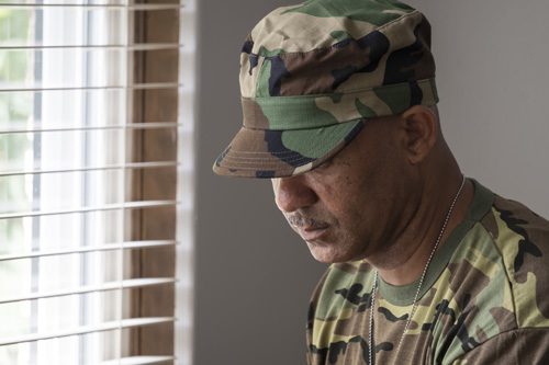 Drug-and-Alcohol-Abuse-in-the-Veteran-Community - man in fatigues at window looking down