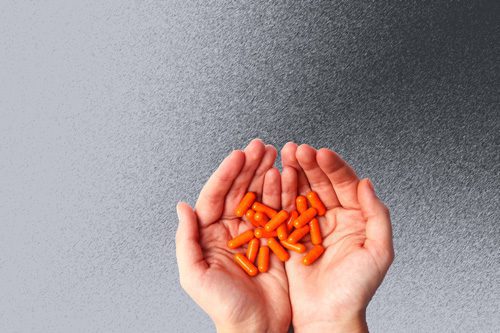 hands full of orange capsules pills