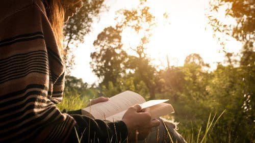 woman reading book outside