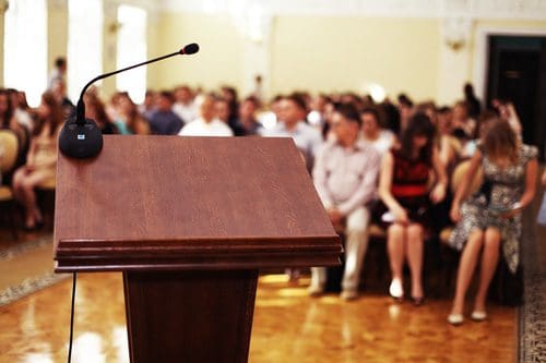 podium and crowd at 12 step meeting - giving back