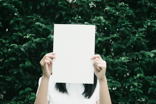 young woman holding a blank sheet of white paper in front of her face - children of addicts