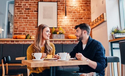 two young adults on a date at a coffee shop - love