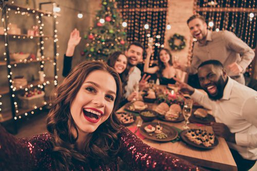 girl taking selfie with group of friends at holiday party - sober