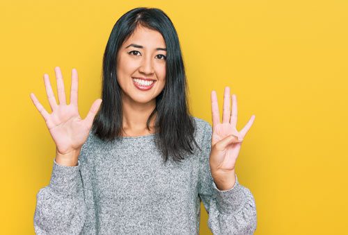 pretty smiling woman holding up 9 fingers on bright yellow background - relapse prevention
