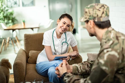 smiling female nurse talking to man in military fatigues - addiction and veterans