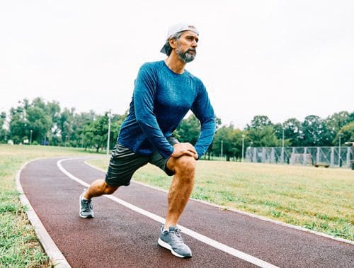 very handsome older man stretching to jog on a track - cravings