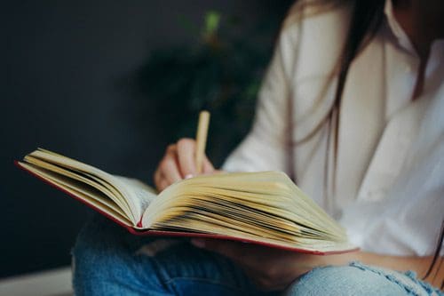 cropped shot of young woman writing in a journal - journaling