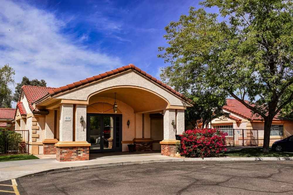 Exterior of Canyon Vista Recovery Center, a single-story building with a red-tiled roof, surrounded by trees and landscaping under a blue sky.